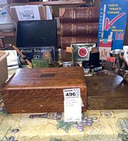 Full view of the wooden boxes, decorative carved box, and background items including encyclopedias and cigarette packs.