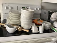 Full view of stacked plates, bowls, gravy boat, rolling pin, butter dish, sugar bowl, and cheese grater showing the complete lot contents