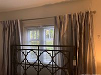 Curtain rod mounted above window holding two striped drapes.