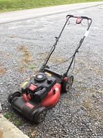 Full view of Craftsman gas powered lawn mower on gravel surface showing handle and body.