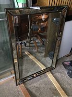 Full view of rectangular framed mirror standing upright showing reflective surface and frame detailing.