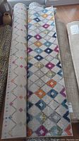 Rolled rug among others showing overall diamond-pattern design