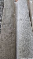 Rolled up beige IKEA Englesborg rug alongside its backside showing woven texture and beige/grey flecks.