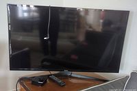 Front view of Samsung 40 inch TV on table showing screen and remote controls nearby.