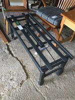 Full view of the black painted wooden washtub stand with slatted top and four legs.