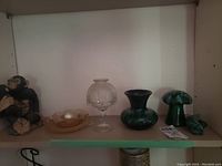 Shelf with various Blue Mountain Pottery pieces, glass candy dish, brown dish, and ceramic monkey figurine