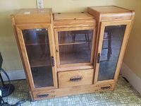 Full front view of the maple wood hutch cabinet showing the glass doors, drawer, and wood top sections.