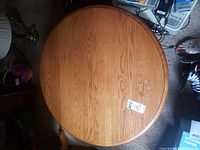 Top view of the round wooden coffee table showing wear and marks on the surface.
