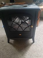 Front view showing the decorative window front and artificial log detail inside the electric fireplace stove.