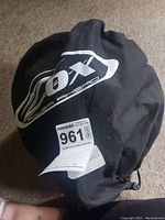 Black drawstring carrying bag with white OX Power Ahead logo, contains helmet inside.