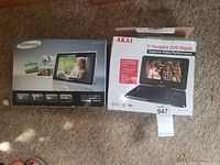 Photo of both boxes showing Samsung digital photo frame and Akai portable DVD player