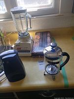 Photo showing blender, electric can opener, and food sealer box on kitchen counter