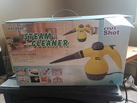 Original boxed Hot Shot Enviro Steamer hand steam cleaner, showing product image and usage examples on box.