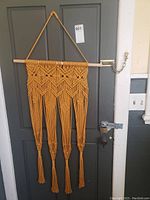 Yellow macrame wall hanging hanging on door, showing pattern and tassels