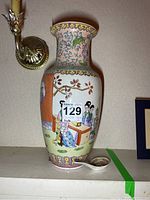 Front view of the Chinese porcelain vase with painted figures and attached auction label.