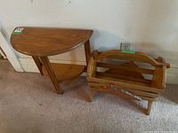 View of wooden demi lune table and wooden magazine rack side by side against wall