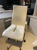 Full view of BoConcept office desk chair showing white ribbed leather upholstery and silver metal base with casters. Leather on seat is visibly peeled and worn.