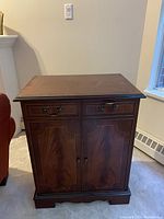Front view of closed mahogany stereo cabinet showing two drawers with brass handles and two paneled doors.