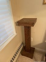 Side view of oak plant stand showing water stains on top and wood grain.