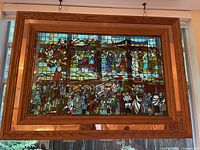 Full view of framed stained glass panel depicting Jewish wedding scene hung in window