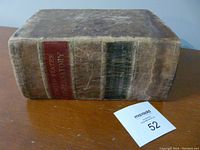 Photo of the antique book showing the spine with title and edition details on a worn leather cover.