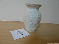 Front angled view of ivory Belleek vase showing floral relief pattern and flared rim.