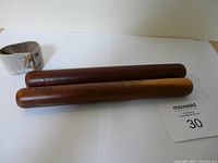 Photo showing the pair of wooden rhythm sticks with leather tie on a white background with a lot number card.