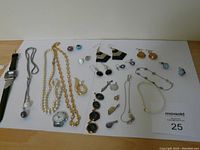 Lot overview showing watches, earrings, necklaces, bracelets, pins, and charms arranged on a flat surface