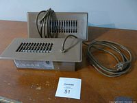 Two Cyclone booster fans placed on a wooden surface showing vented front, attached power cords, and metal casing.