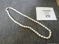 Full strand of white fresh water pearls laid out flat, showing the full length of the necklace and clasp.