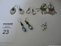 Photo showing four pairs of silver earrings with colored stones and hooks arranged on a flat surface.