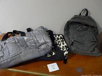 Photo shows all three bags side by side on a flat surface: Vans grey denim backpack, DKNY large grey puffy tote, and Joe Boxer animal print tote.