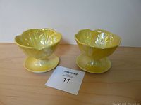 Pair of yellow iridescent glazed ice cream bowls shown front view on wooden surface