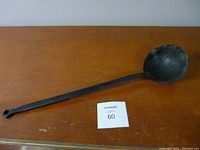 Full view of the vintage cast iron ladle showing the entire length and bowl shape