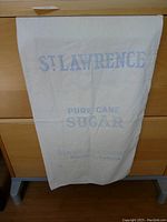 Full view of the vintage sugar sack hanging showing branding and general condition.