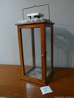 Full view of the wood and glass outdoor lantern showing its rectangular shape, metal top, and latch door.