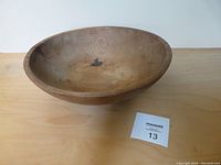 Photo of vintage wooden bowl showing overall shape and signs of wear including staining and split edge.