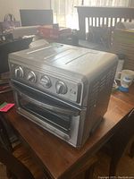 Front view of stainless steel toaster oven air fryer with four control knobs and glass door with handle