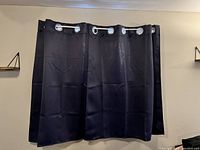 Photo of navy blue curtains with silver metal grommets hung on a rod, showing fabric texture and folds.
