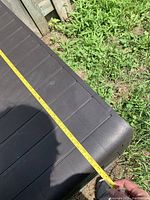 Top-down view of brown plastic storage bin with a yellow measuring tape showing approximately 36 inches width.