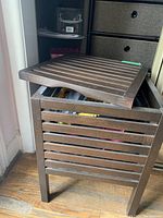 Wooden storage table with a slatted top showing the removable top surface and open storage below.