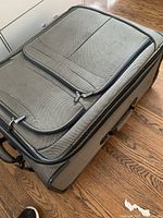 Gray fabric suitcase closed on wooden floor