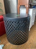 Side view of one black metal round side table with lattice sides, showing metal construction and finish.