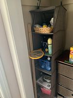 Two brown fabric hanging closet shelves filled with cleaning and household items