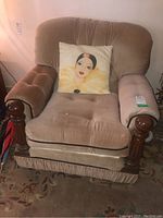 Front view of beige fabric armchair with wooden frame, showing decorative pillow and overall shape.