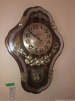 Full view of vintage wall clock with wood and gold decorative details, clock face visible