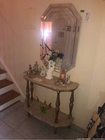 Side view of the wooden console table with marble shelves and various decorative items placed on top and bottom shelves. The console features turned legs.