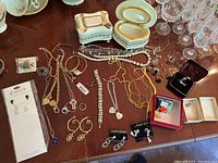 Overview of assorted costume jewellery laid out on a table including necklaces, bracelets, earrings, rings, and two decorative jewellery boxes.