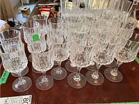 Front view showing several of the crystal wine glasses in two sizes with visible cut patterns and stems on a wooden table.