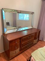 Full view of the vintage wood dresser with mirror on top, showing three central drawers with metal handles and two side cabinets with curved glass fronts and drop pull handles.